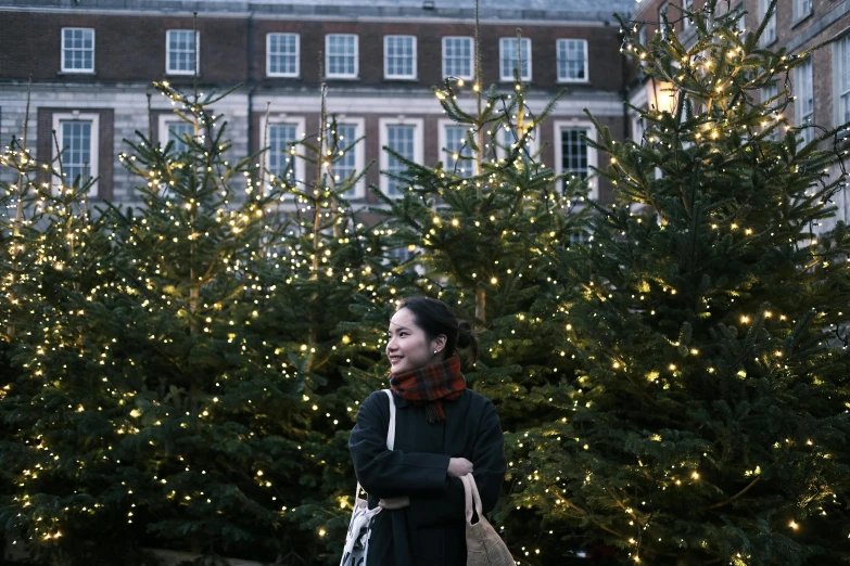 a woman standing in front of christmas trees