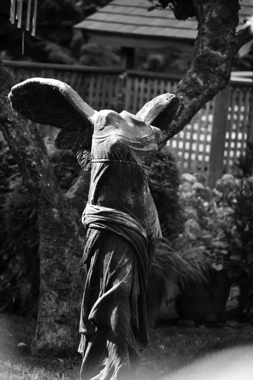 statue of an elephant holding a large piece of cloth near trees