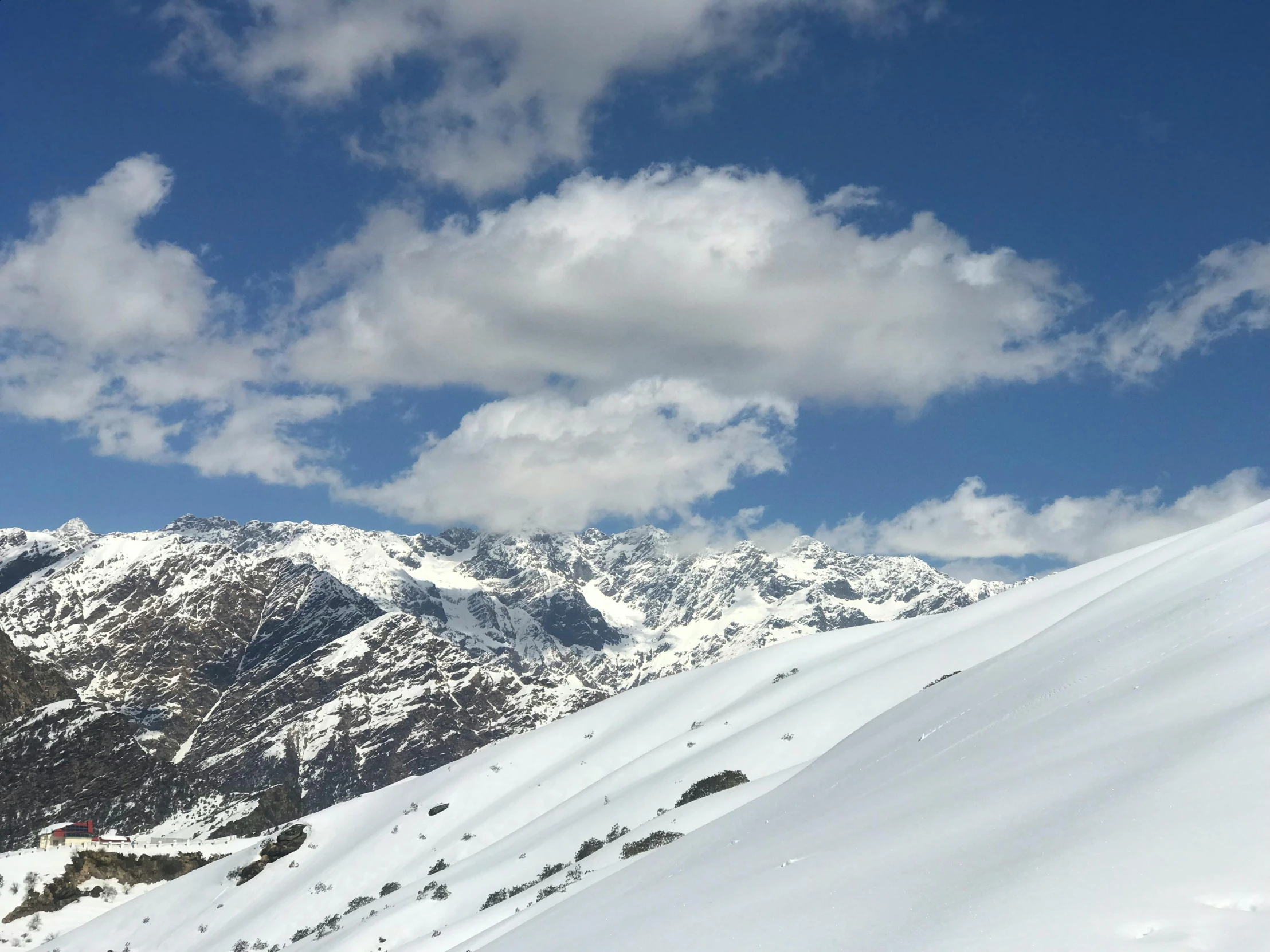 a snow covered mountain with clouds above it