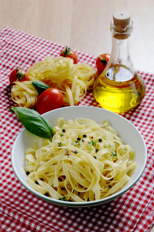 a bowl of pasta with tomatoes on the side next to olive oil and cherry tomatoes