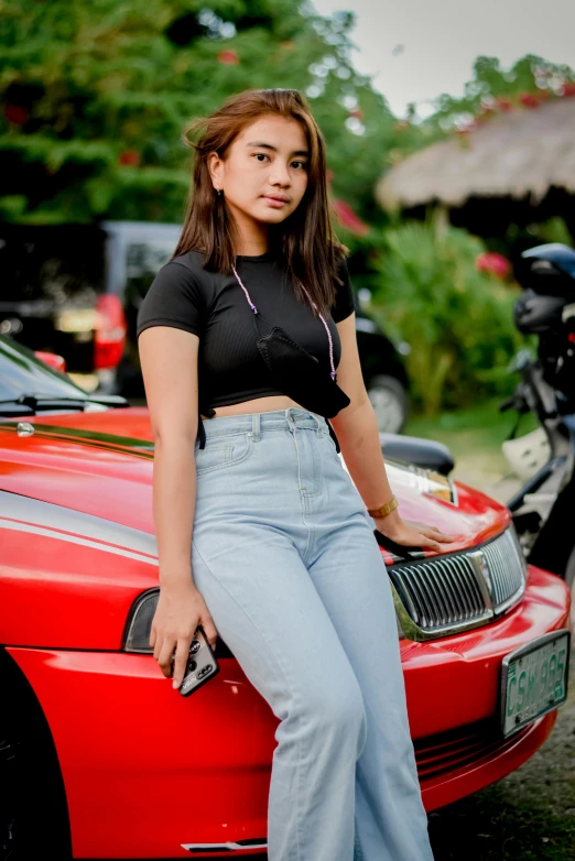 a woman in high - rise jeans standing next to her car