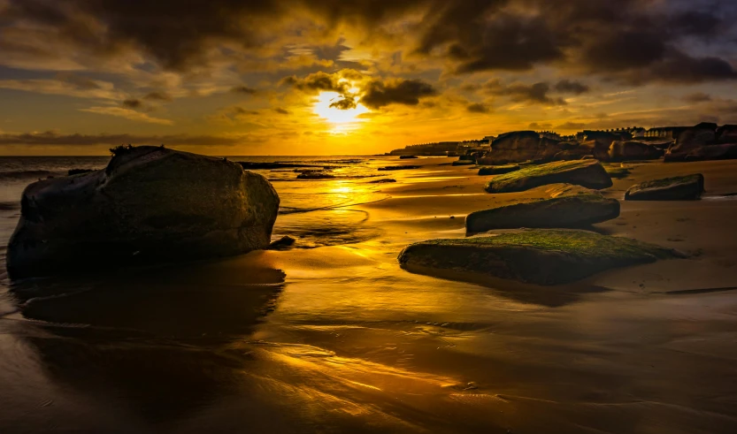 sunset at beach with large rocks laying on beach