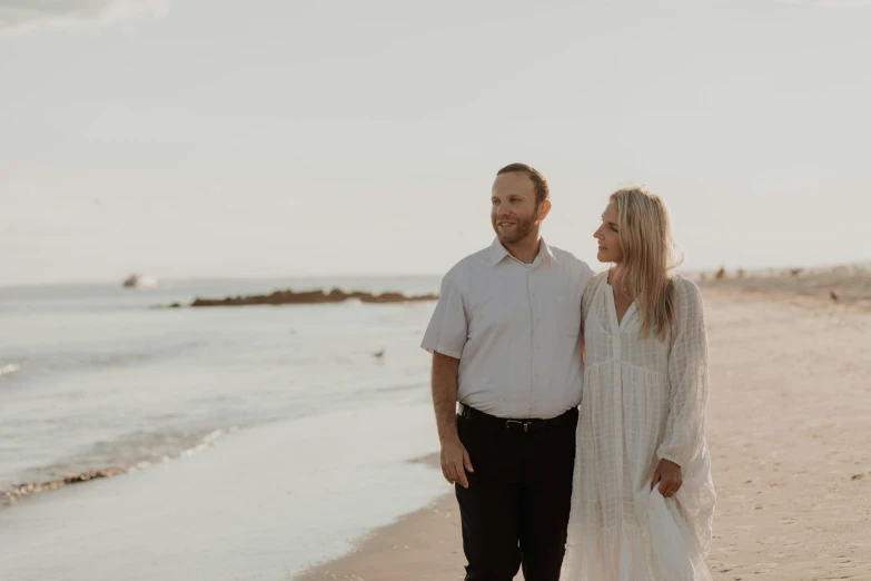 a woman holding hands and standing next to a man on the beach