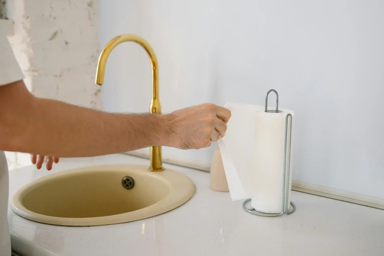 a person holding toilet paper in front of a sink