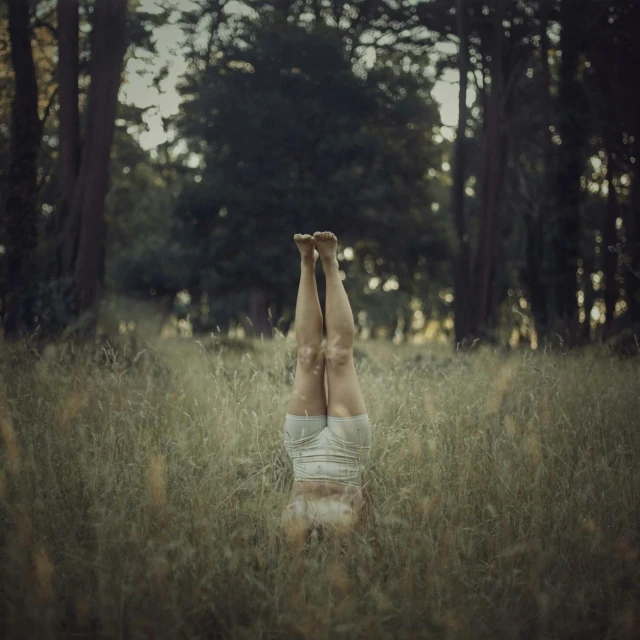 a woman in white underwear laying in the grass with her hands raised