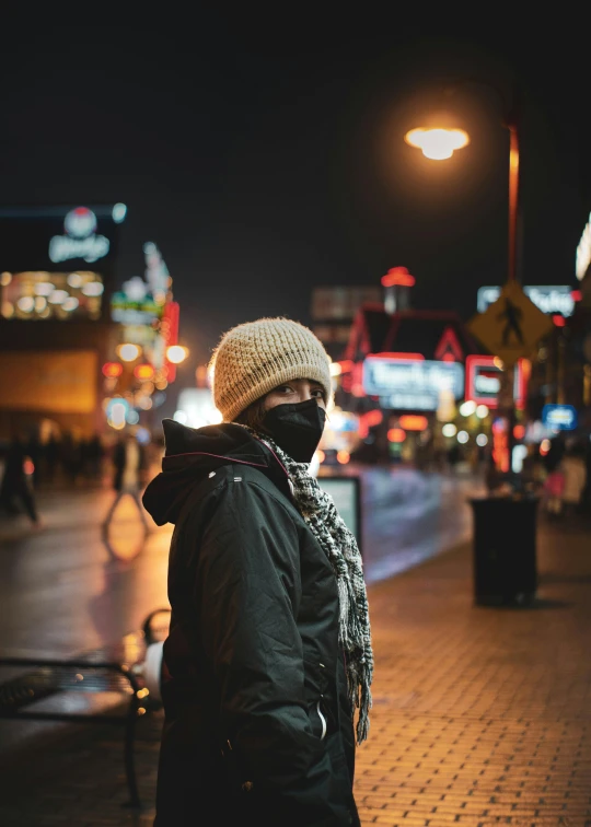 a woman stands on the side of the street in front of a bus stop