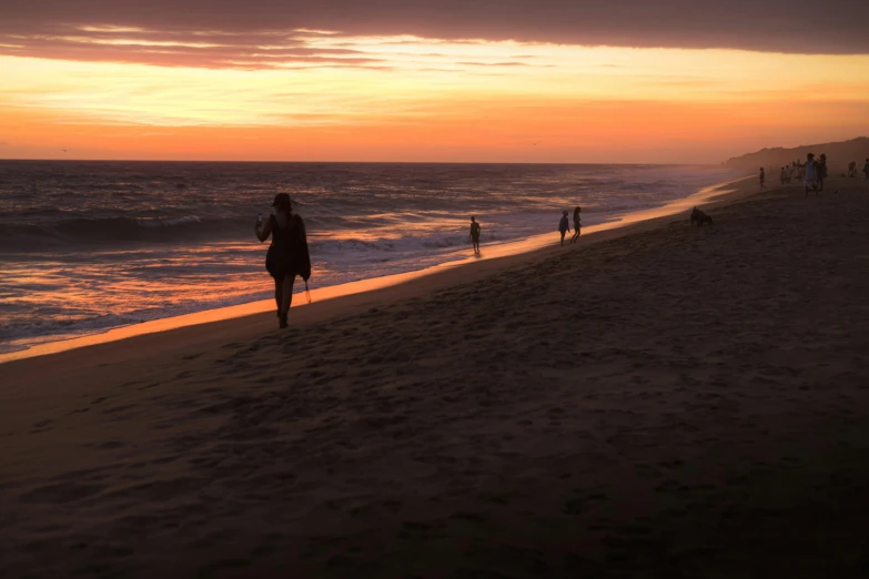 a couple of people walking down a beach