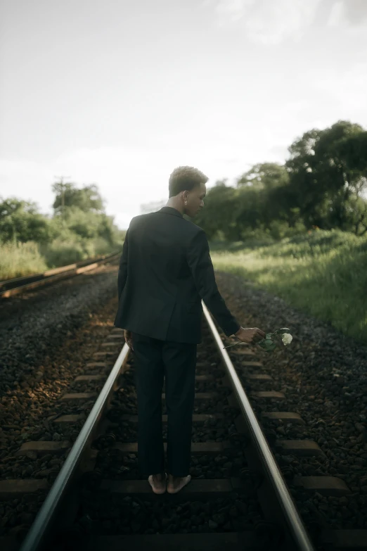 a man standing on the railroad track wearing a suit