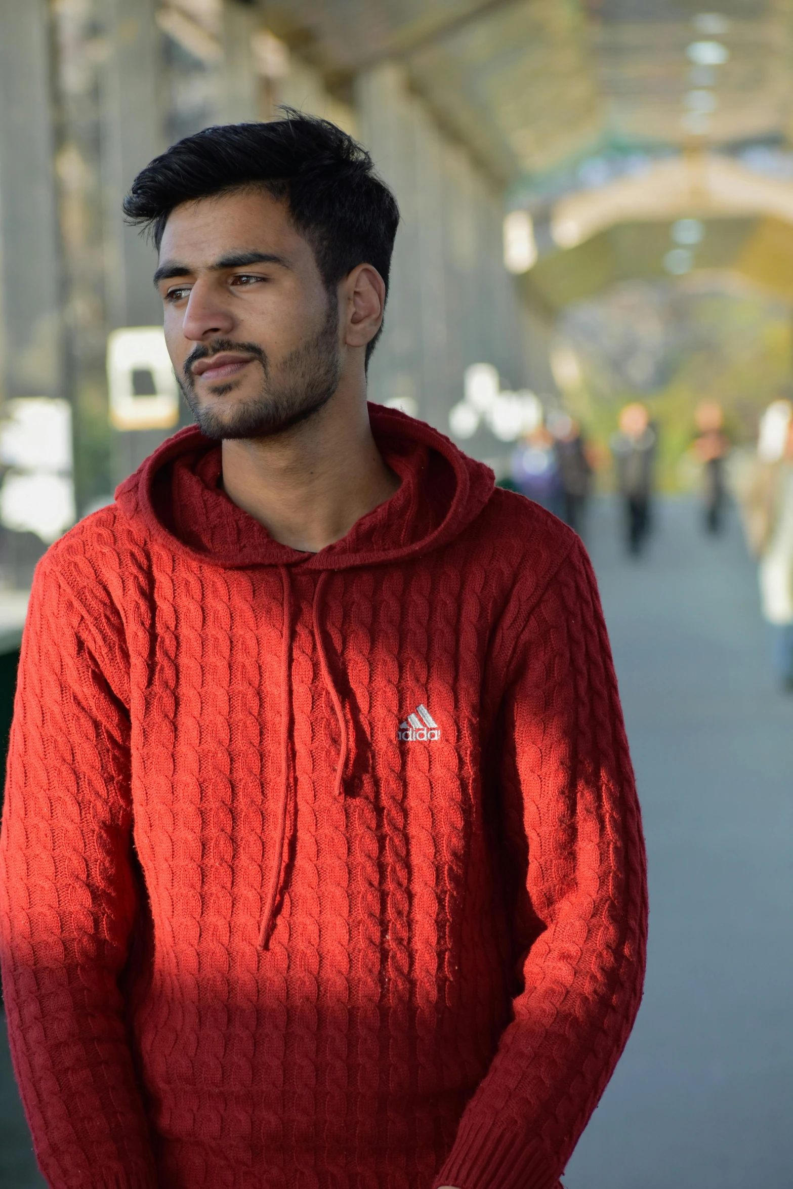 the man in the red sweater is waiting for the train to arrive