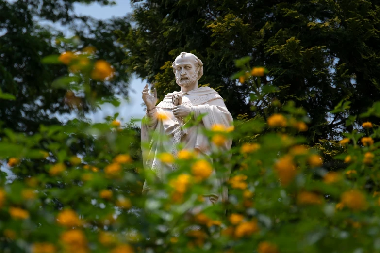 a statue of a monk in a garden setting