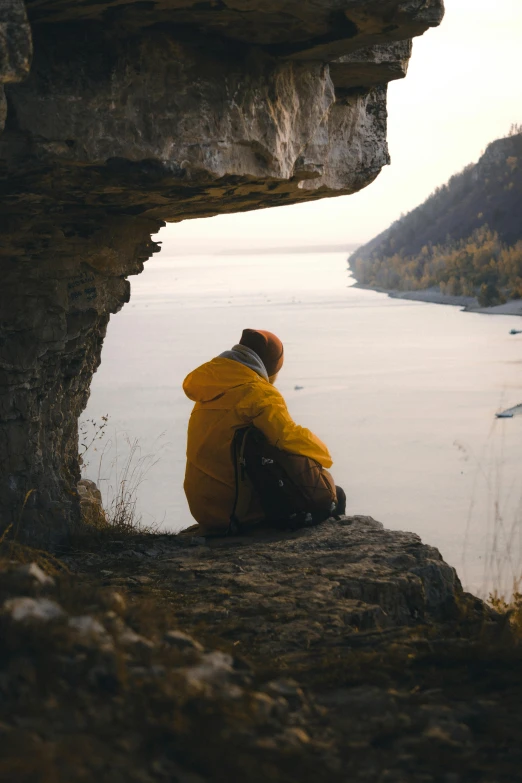 a person sitting on a rock near the water