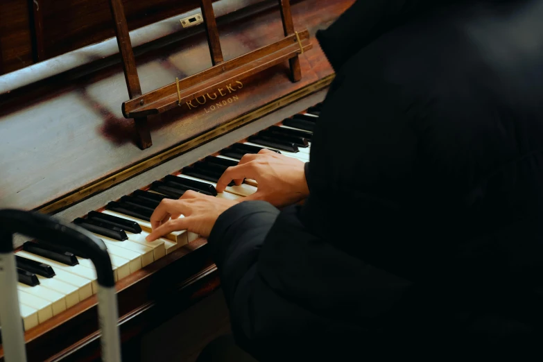 a person with black coat playing the piano