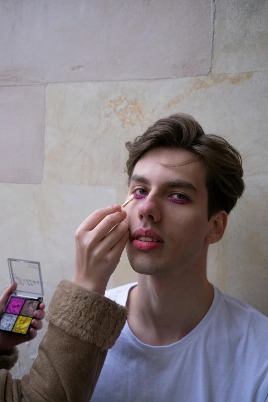 a man taking a picture of his face with his makeup brush