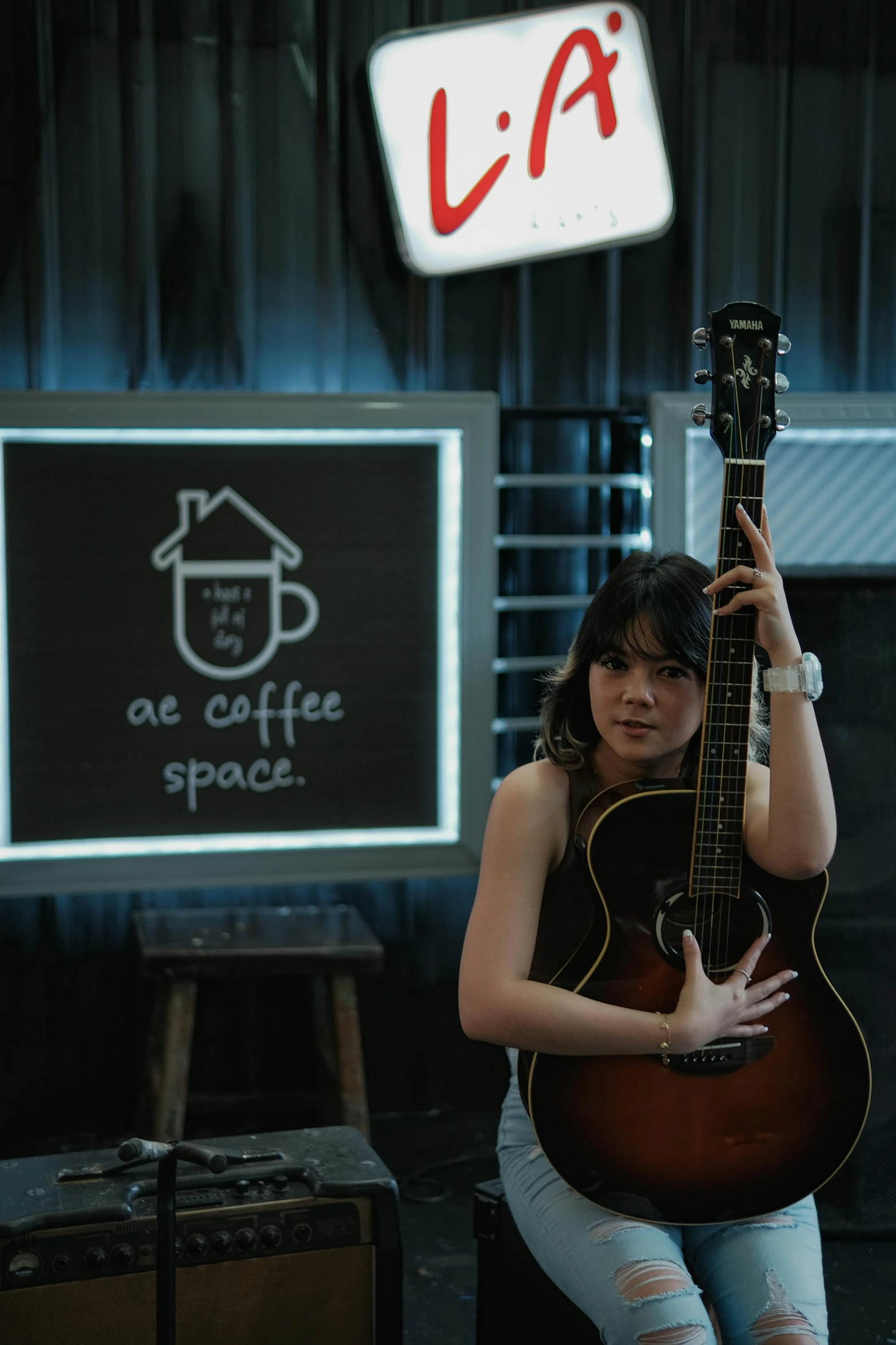 woman holding up an acoustic guitar inside a store