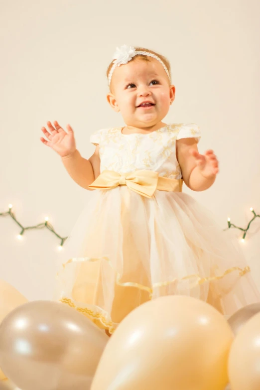 a smiling toddler in a party dress among balloons