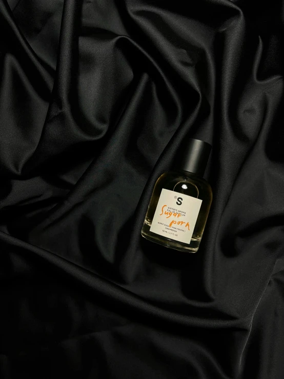 a bottle of liquid sitting on top of a black cloth