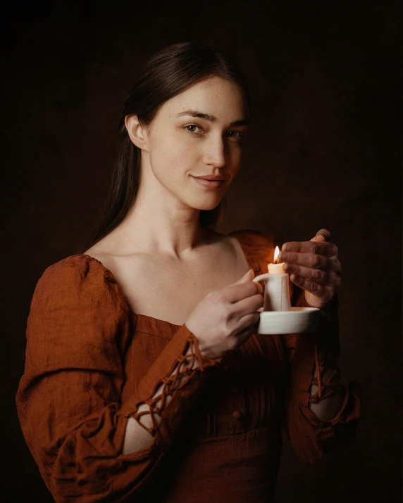 a woman holding a teacup with a lit candle