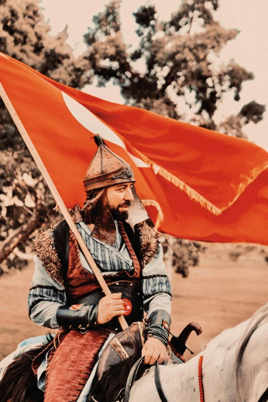 a soldier is on horseback carrying an orange flag