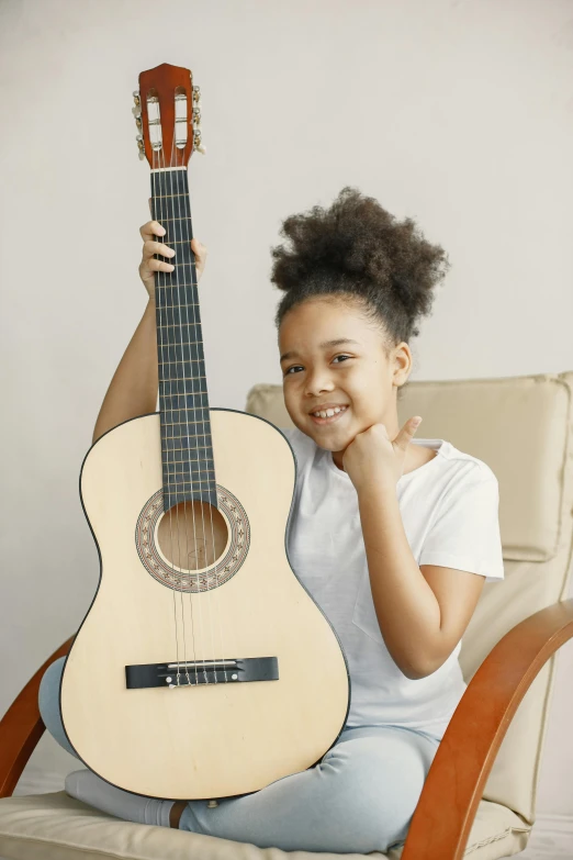 a child holds an acoustic guitar by her face