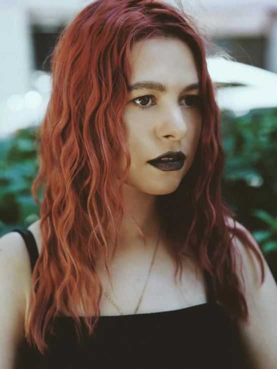 a woman with long red hair and black lipstick