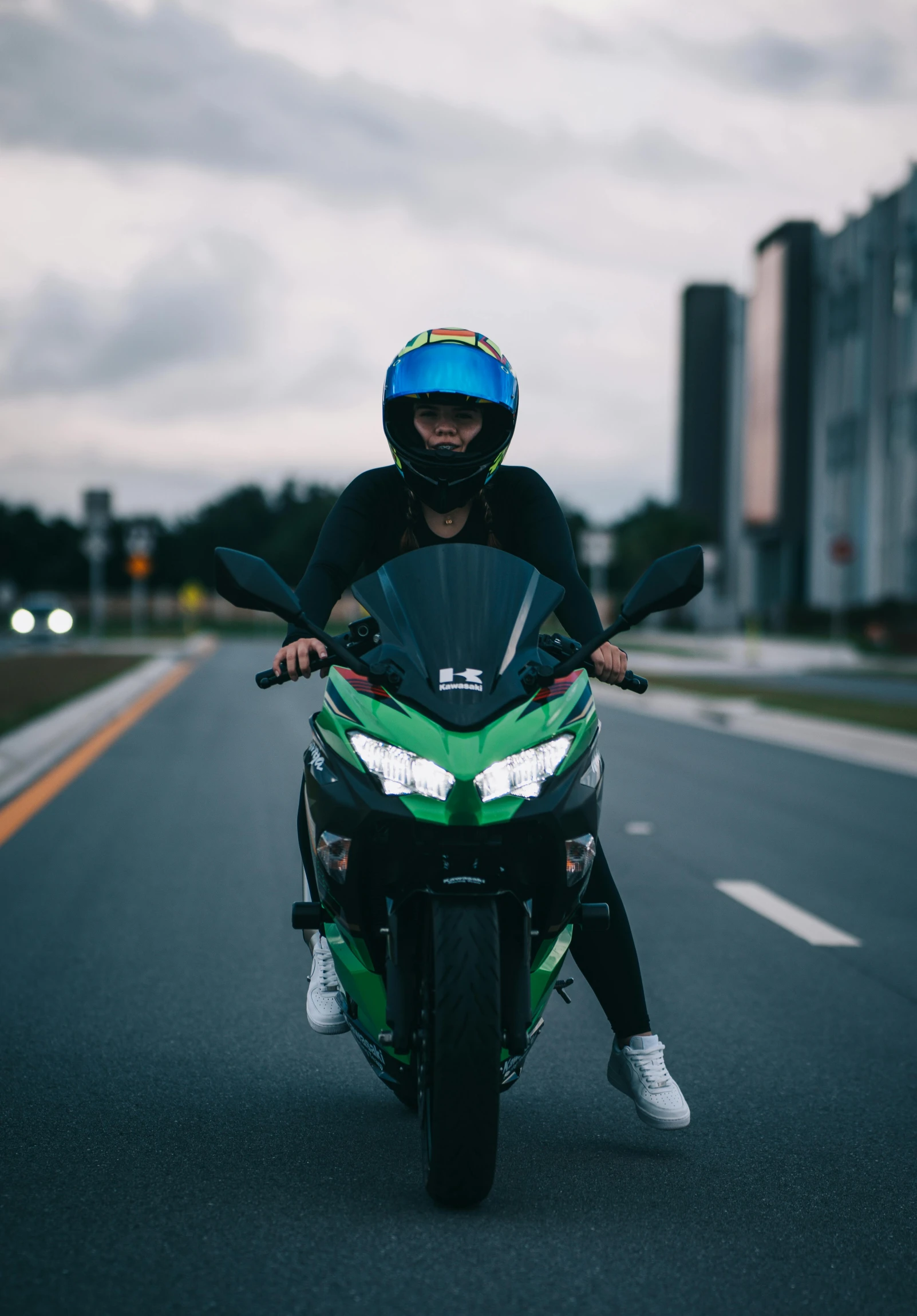 a person riding a green motorcycle on the street