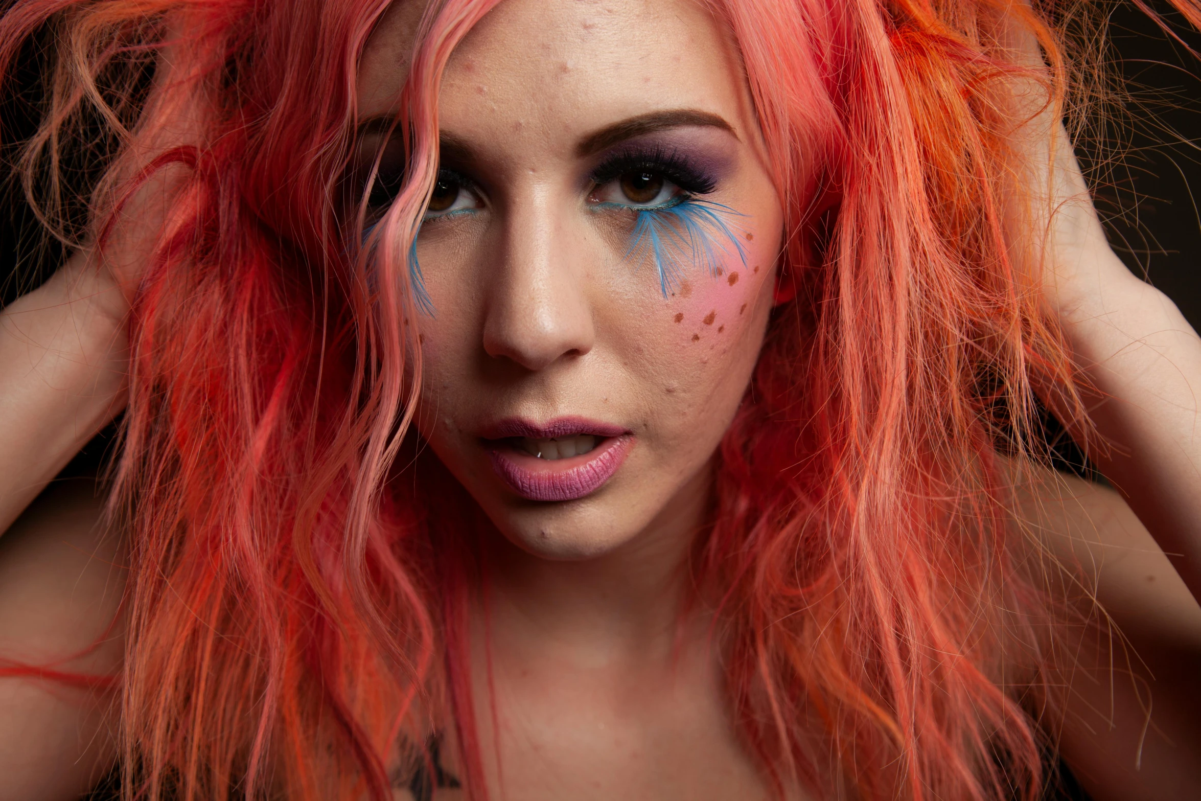 a young woman with pink hair has blue eyes