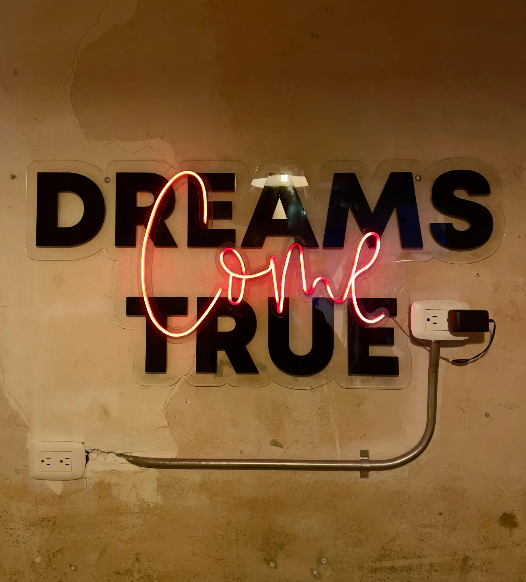 a neon sign in the shape of words reads dreams come true