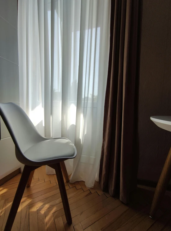 a chair with white curtains and wooden floor
