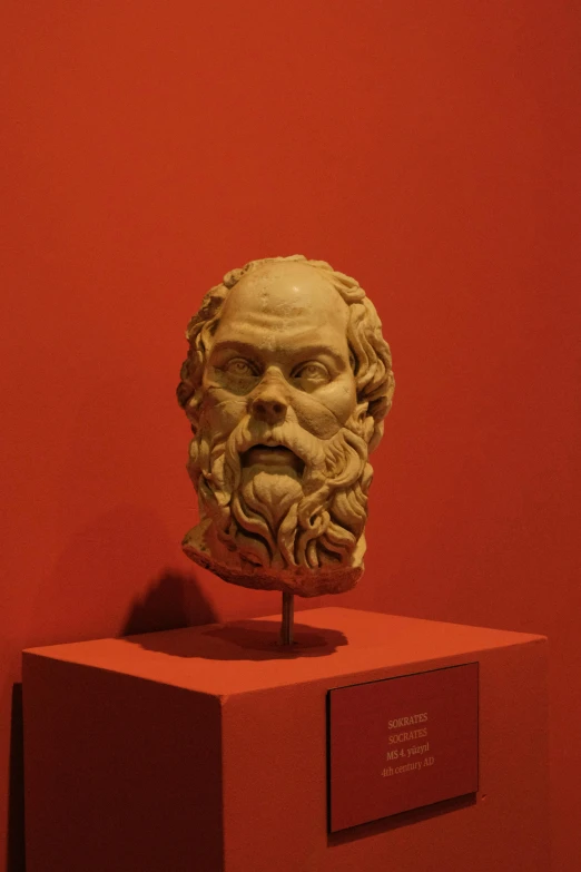 a statue of a man with beard wearing a red and yellow colored mask