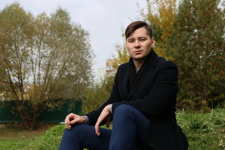 a man sitting in a field with his fingers crossed