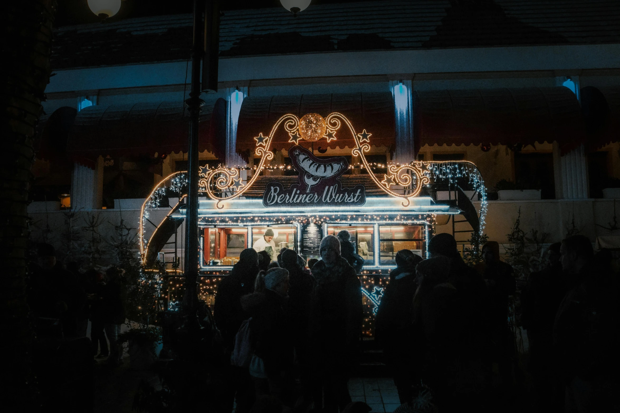 a group of people standing next to a building with christmas lights