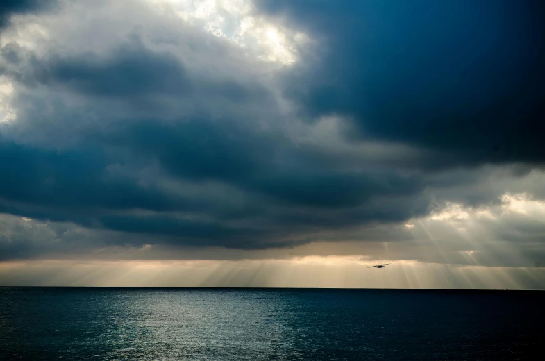 a plane flying high above the ocean in a cloud filled sky