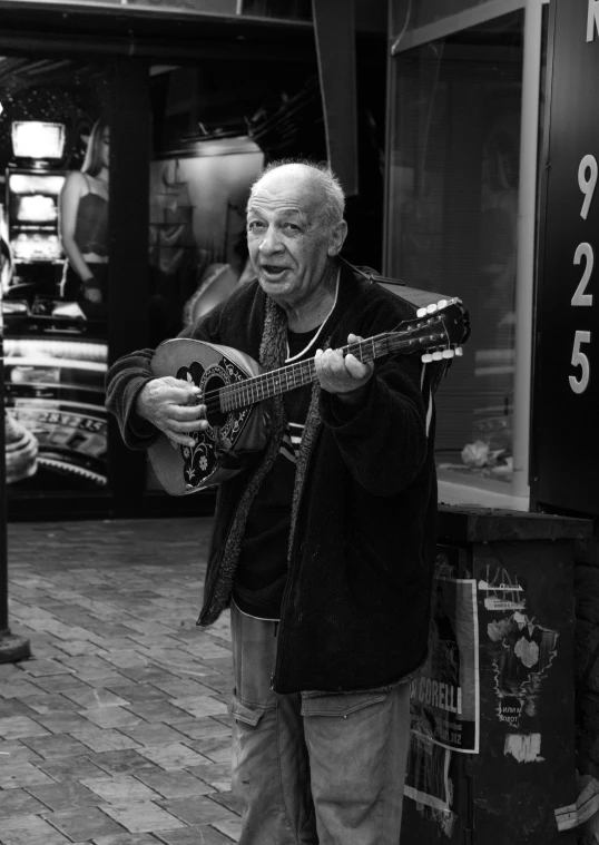 an older man holding a guitar in his right hand