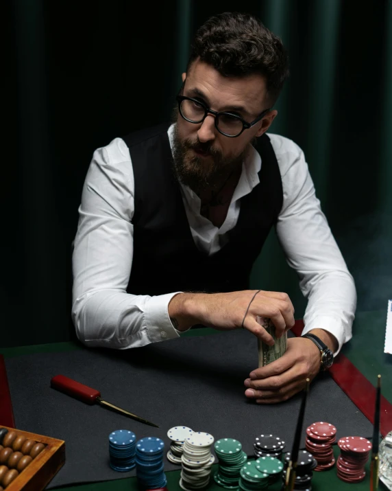 a man sits at a table with a stack of cards and chips