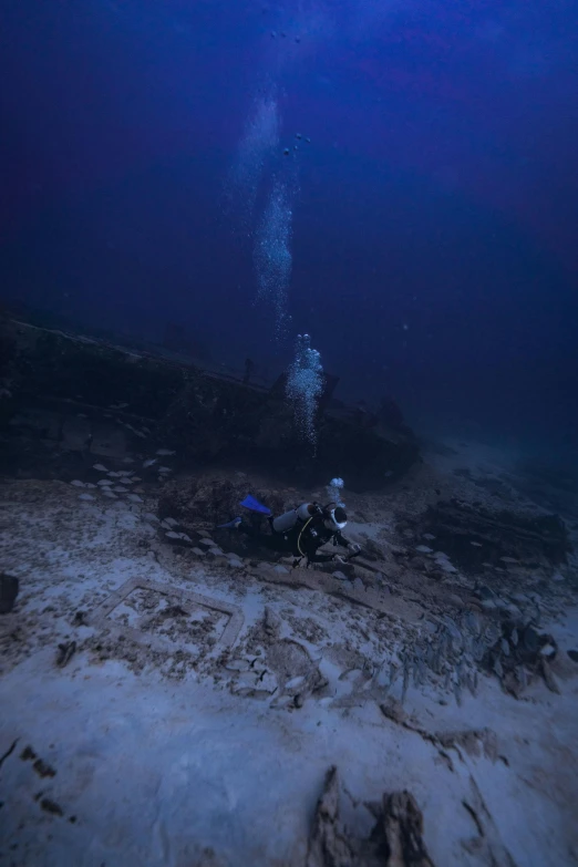 an underwater diving scene with divers watching and observing items