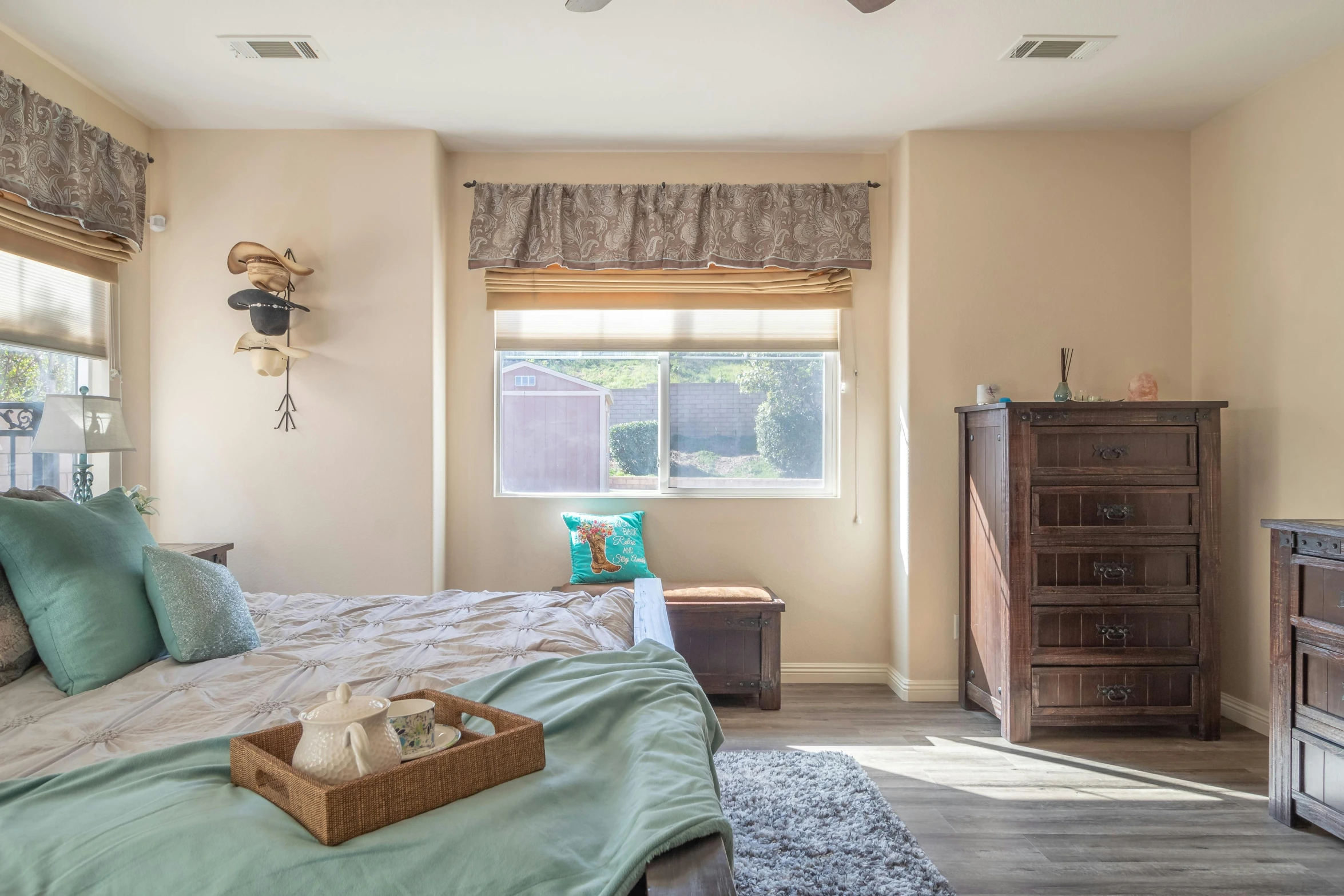 a clean, neat bedroom with a wood dresser and decorative window treatments