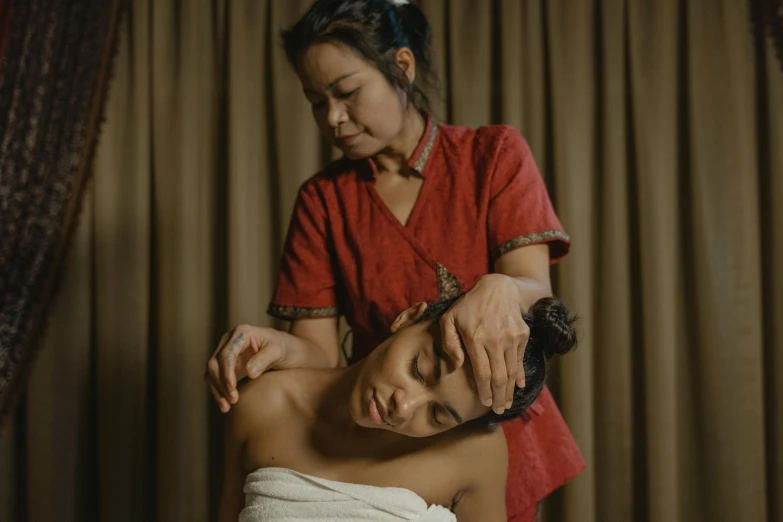 a woman getting an ear massage from another woman