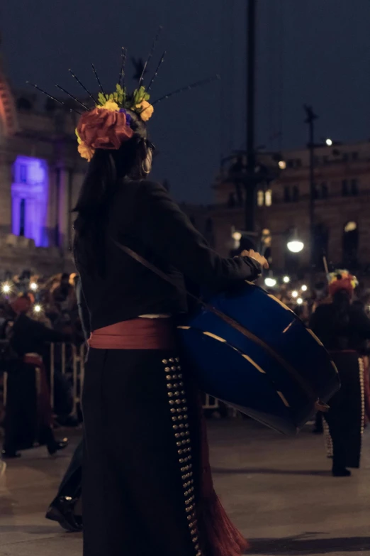 a woman in costume walking in the street with a guitar