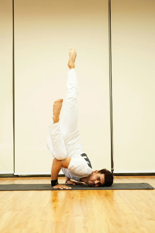 a person in white shirt doing yoga on a mat