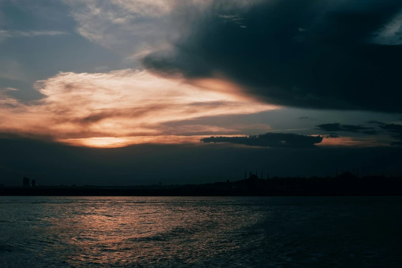 the clouds are setting over the calm water