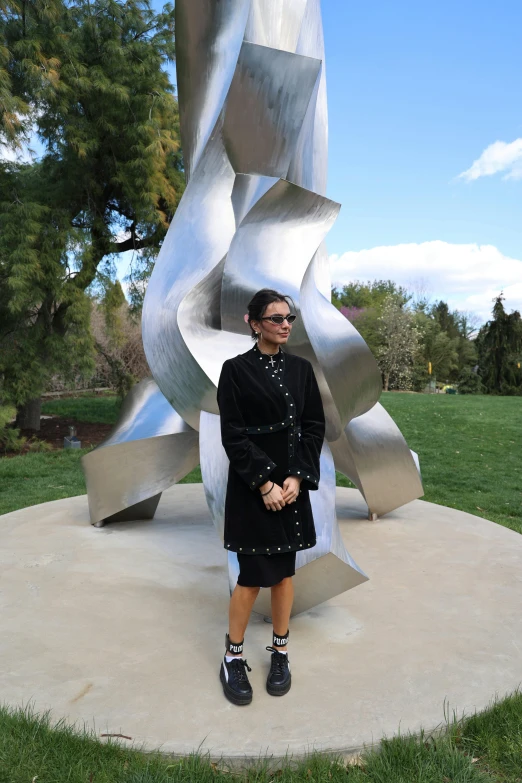 the young person is standing in front of the silver statue