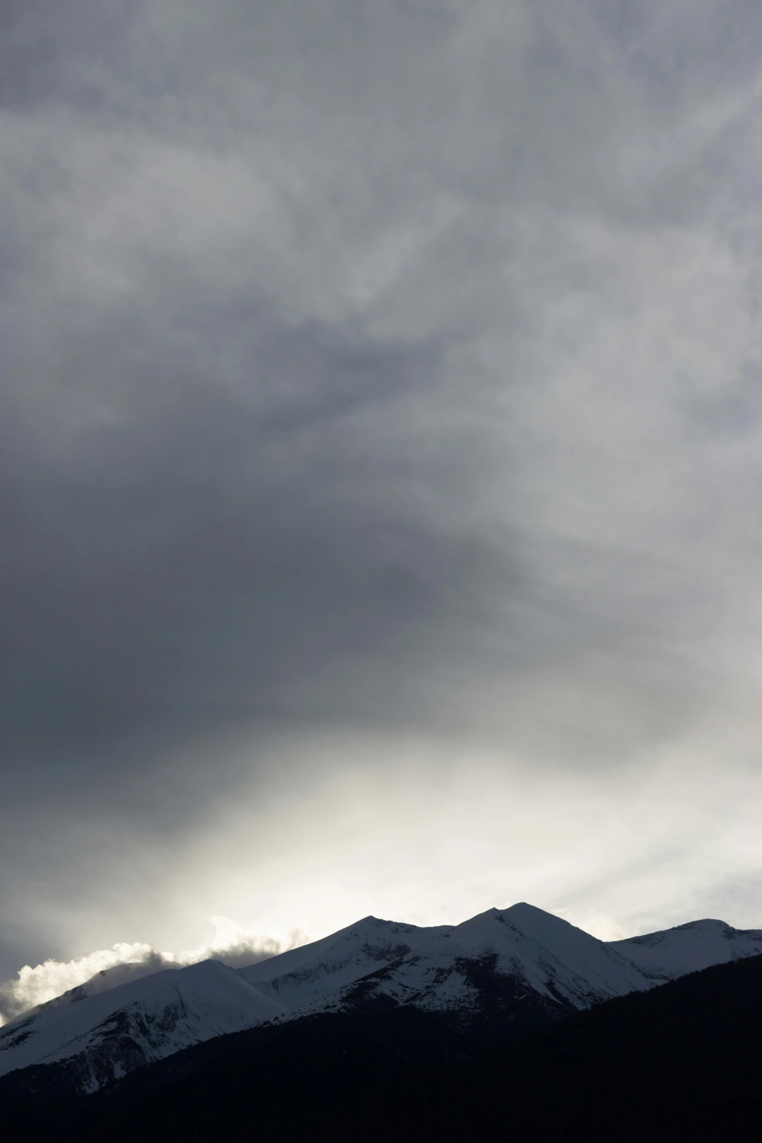 a large group of mountain peaks stand with a cloudy sky