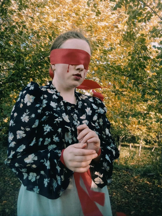 a woman with a blind folded around her head and holding soing in one hand