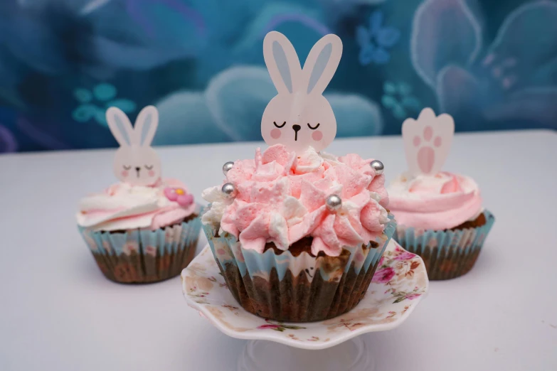 three cupcakes with pink frosting on a table