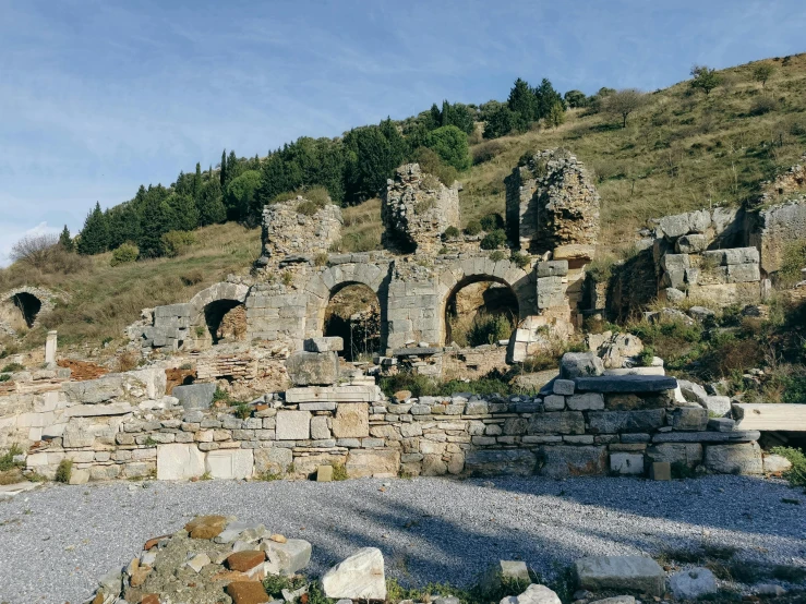 an ancient structure on a rocky surface surrounded by trees and a hill