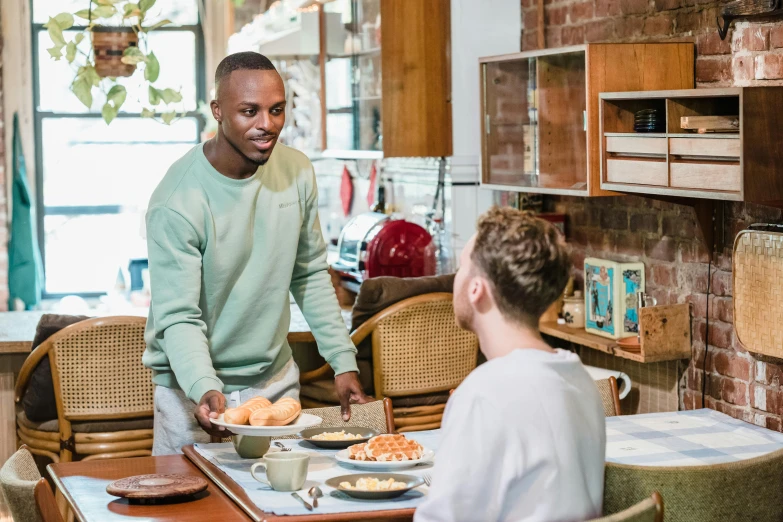 a man is shown smiling and serving food to another man