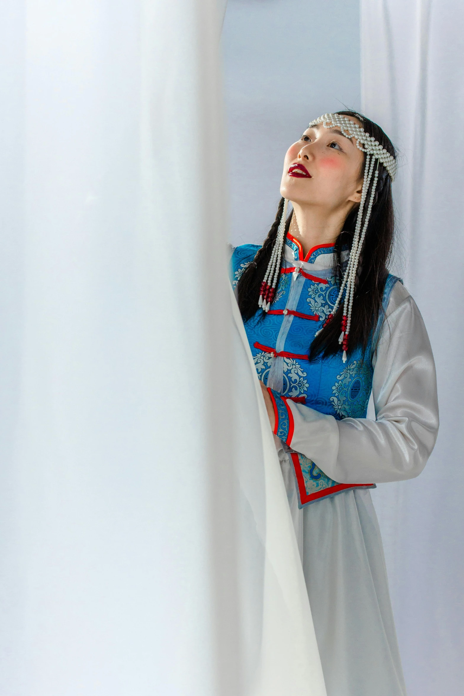 a woman in a dress and beaded headdress looks up