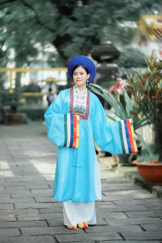 a woman in blue and colorful outfit standing on brick walkway