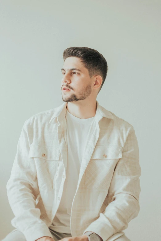 a man sits in front of a white wall