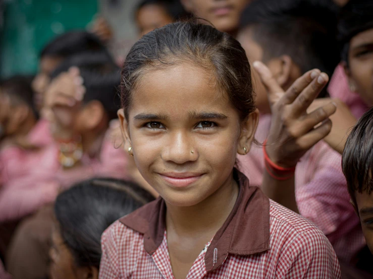 an indian girl standing among her children in red and white shirts